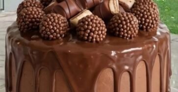 Rich chocolate drip cake decorated with chocolate ganache, chocolate candies, crispy chocolate balls, and macarons.