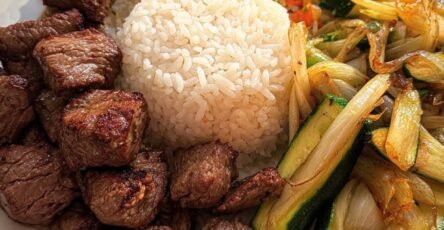 Bistec estilo hibachi con arroz blanco, arroz frito con verduras y calabacín salteado con cebolla en un plato.