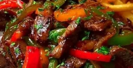 Sizzling beef stir-fry with colorful bell peppers, onions, and crispy French fries served on a plate for an easy homemade dinner.