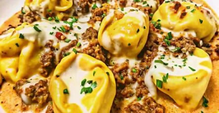 Cheesy garlic beef tortellini served in a creamy Parmesan mozzarella sauce, garnished with fresh parsley in a white bowl.