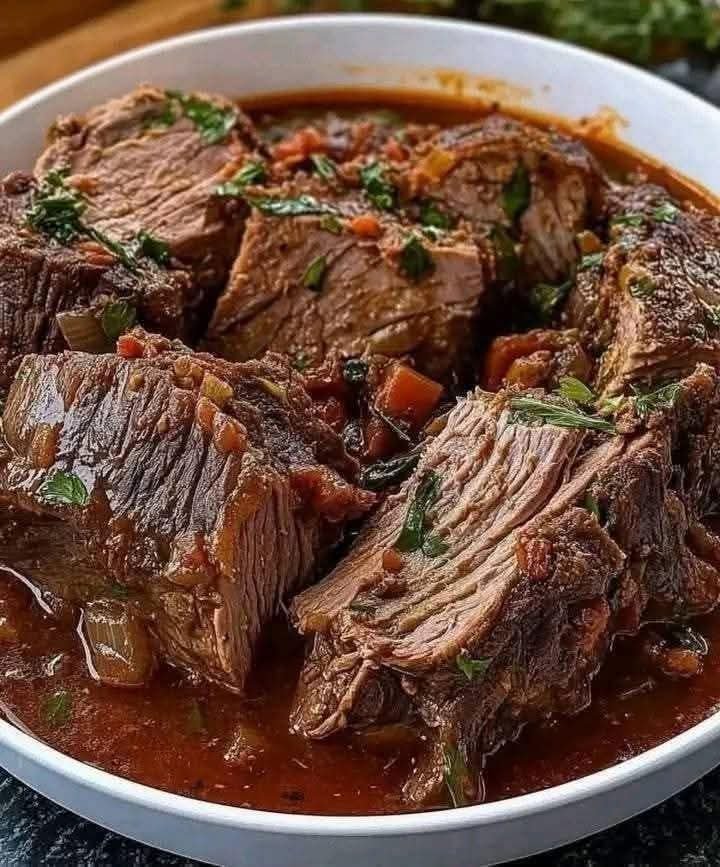 Tender Italian slow-cooked pot roast with beef chuck, tomato sauce, carrots, and fresh herbs