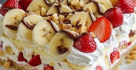 Easy No-Bake Banana Split Cake with bananas, strawberries, whipped cream, chocolate sauce, and hazelnuts
