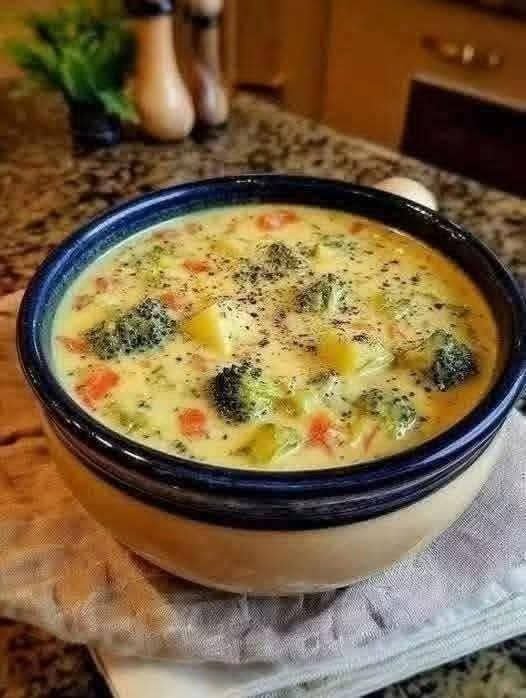 Classic egg drop soup with egg ribbons, carrots, broccoli, and herbs in a bowl