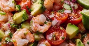 Fresh avocado shrimp ceviche bowl with tomatoes, cucumber, red onion, cilantro, and lime